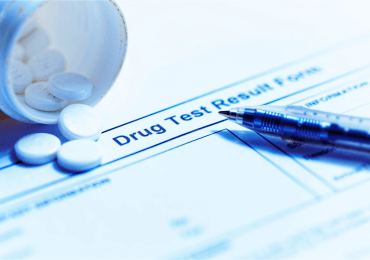a bottle of opioids spill out over a drug test result form