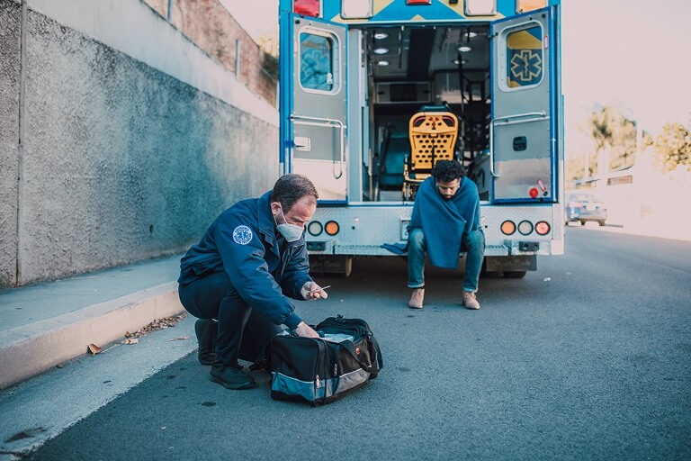 a paramedic checks the bag of a patient on the side of the road