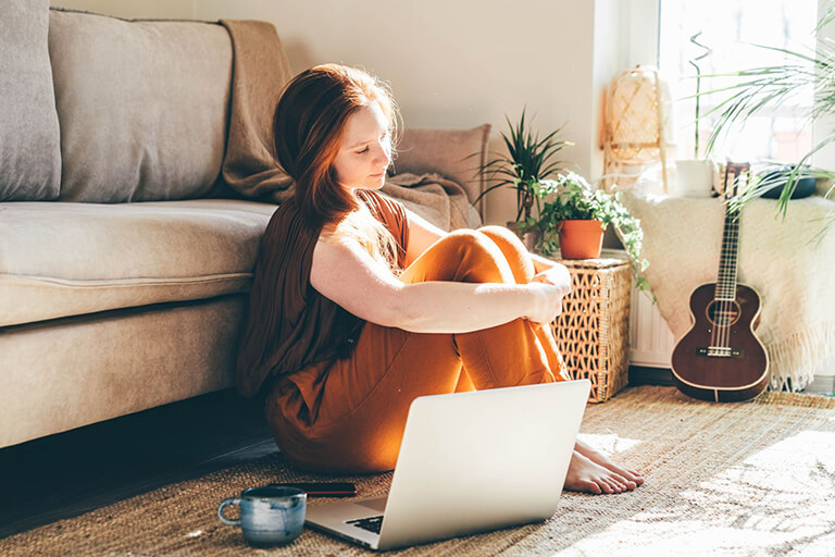 Woman lounging on the floor with an open laptop 