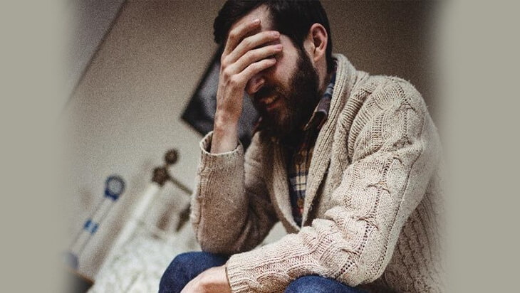 A man covers his eyes in distress