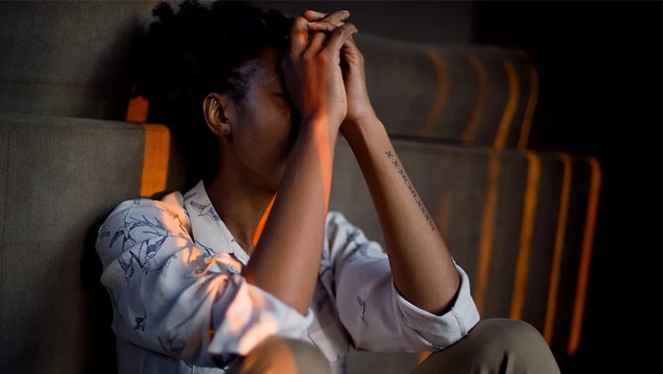 Woman sitting next to the bed, frustrated