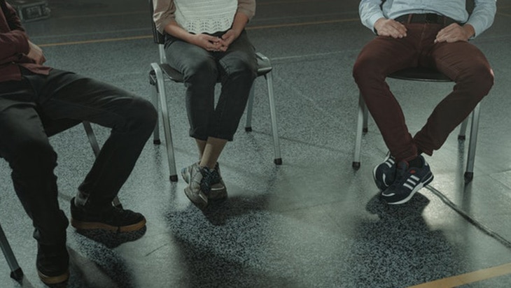 Three people sitting on chairs during a group counselling session