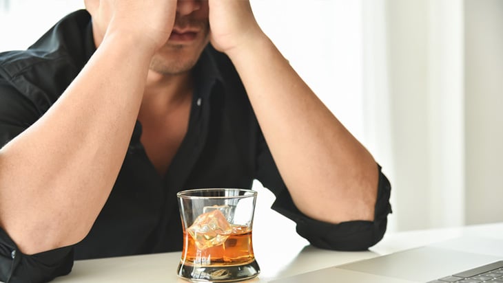 Young man drinking whiskey while working