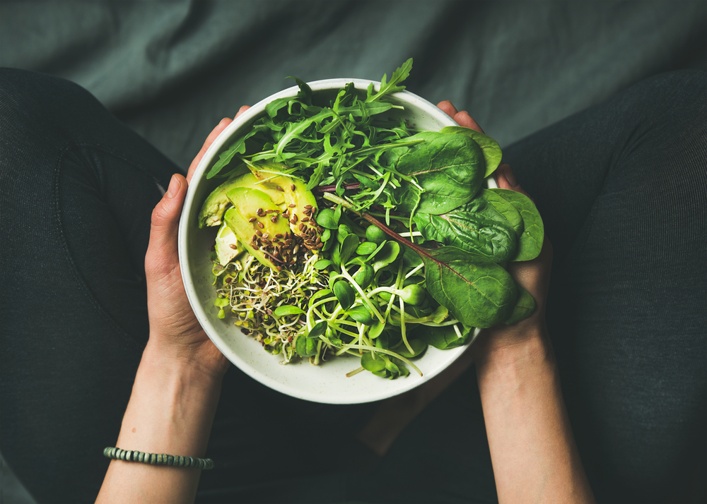 A bowl of leafy greens and sliced avocado
