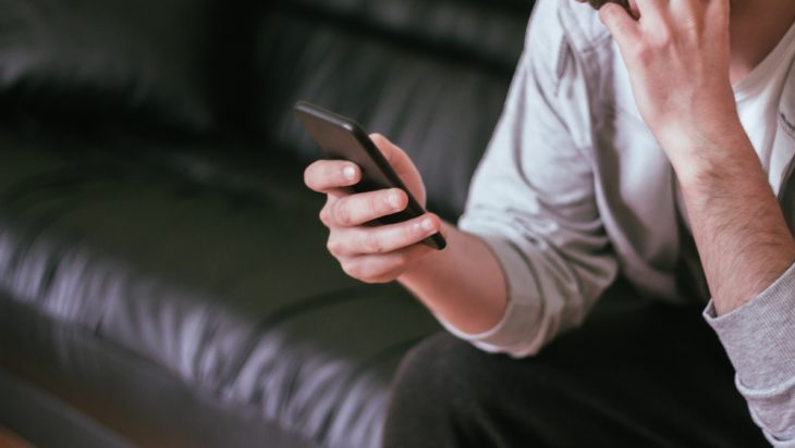 A man sitting on the couch holding his phone