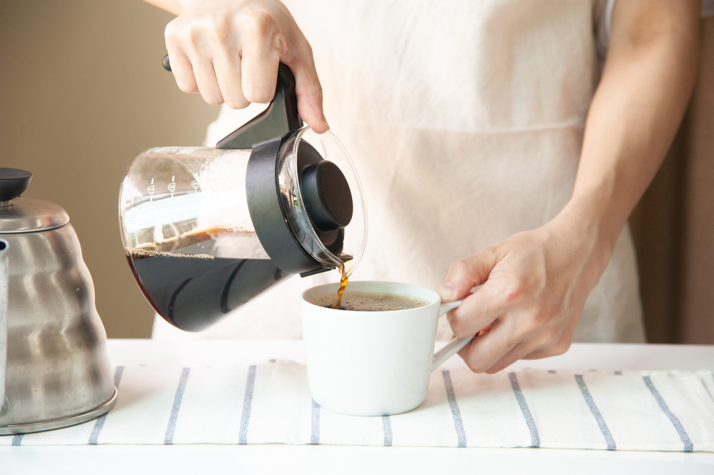 Person making a cup of brewed coffee, one of the many examples of foods good for liver health