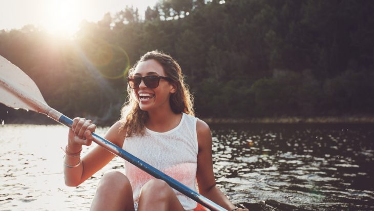 Happy, young woman having fun while kayaking on a lake.