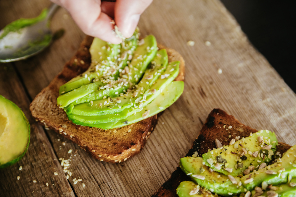 Hands making healthy avocado toast