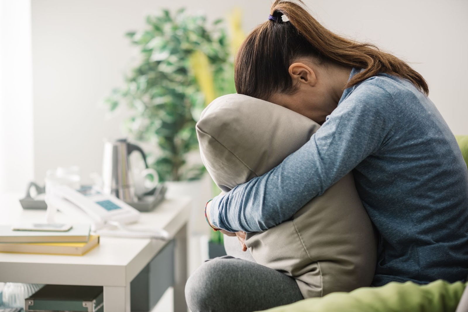 A woman crying on the couch as she experiences withdrawal symptoms