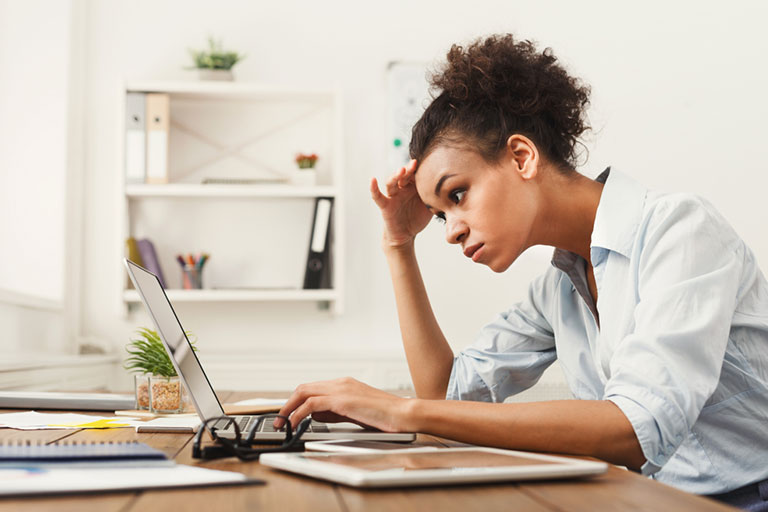 A stressed female employee working in front of her laptop.
