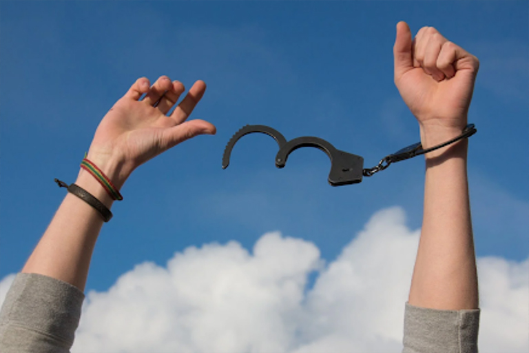 A woman raising her arms to break free from her handcuffs