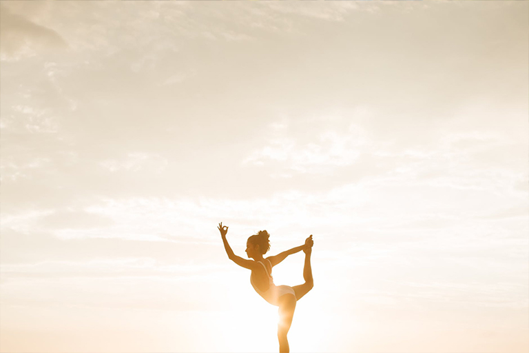 A woman doing outdoor yoga at sunrise.