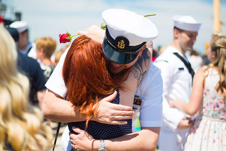 A navy officer embracing his wife before deployment