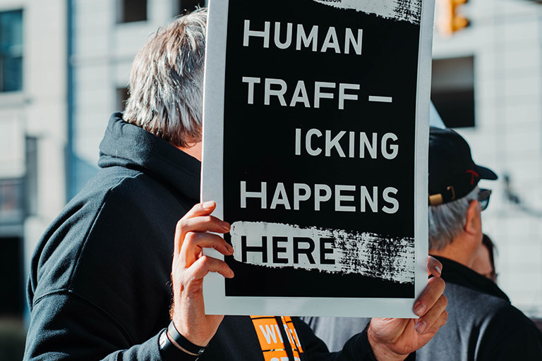 A man holds up a placard that says “Human trafficking happens here