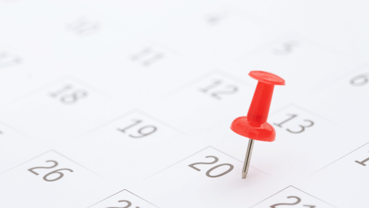 Close up of a calendar with a red pin on a date