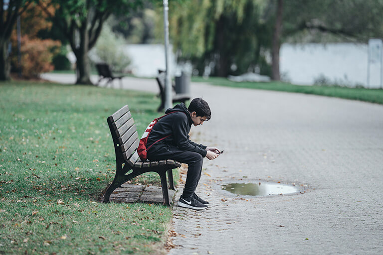 a teenager sitting on a bench alone

