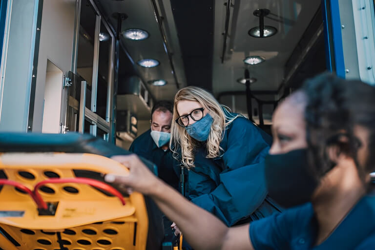 paramedics pull a stretcher out of an ambulance
