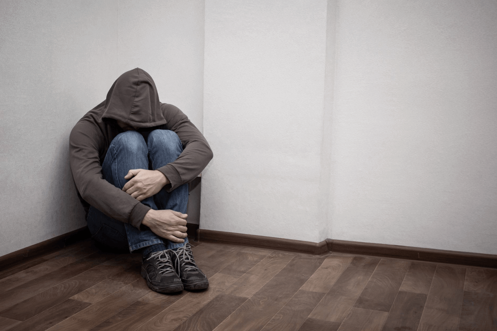 A person curled up in a corner of their room.