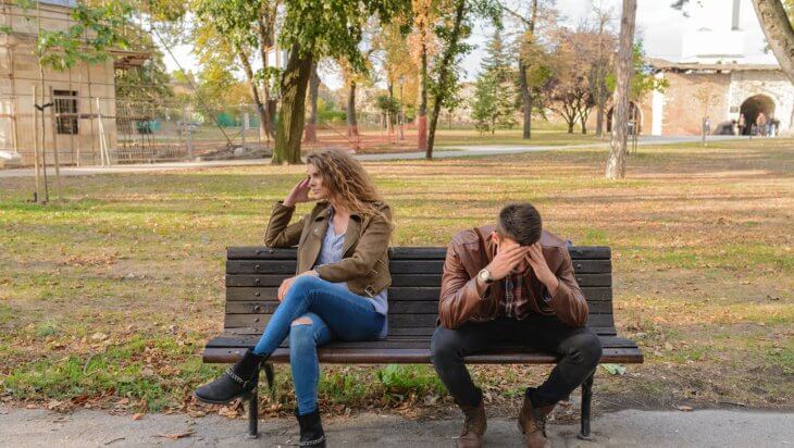 Couple fighting on a bench, turned away from each other
