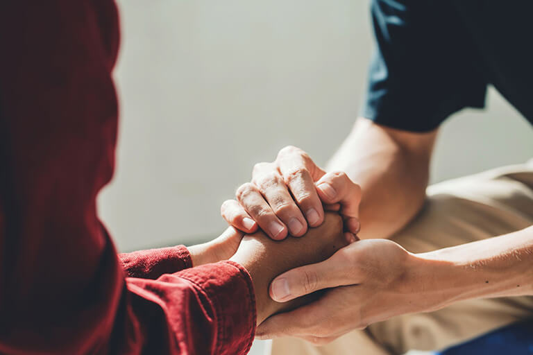 Two people holding each other’s hands as a means of support
