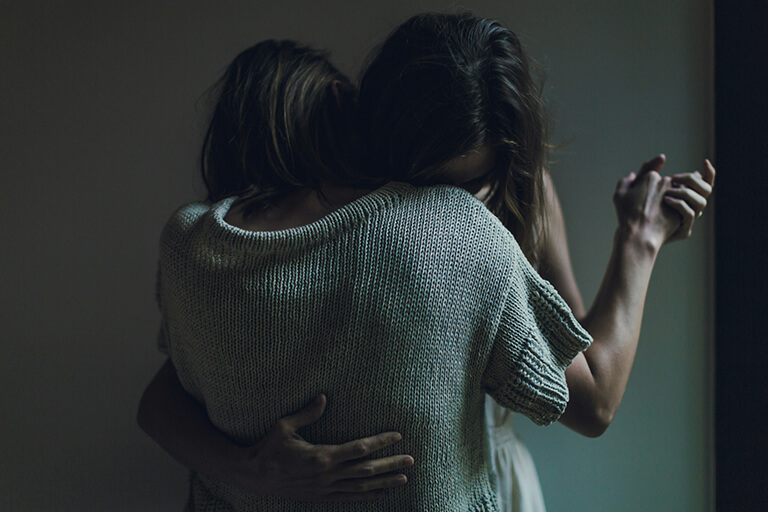 Two women holding each other in a slow dance position in a dark room