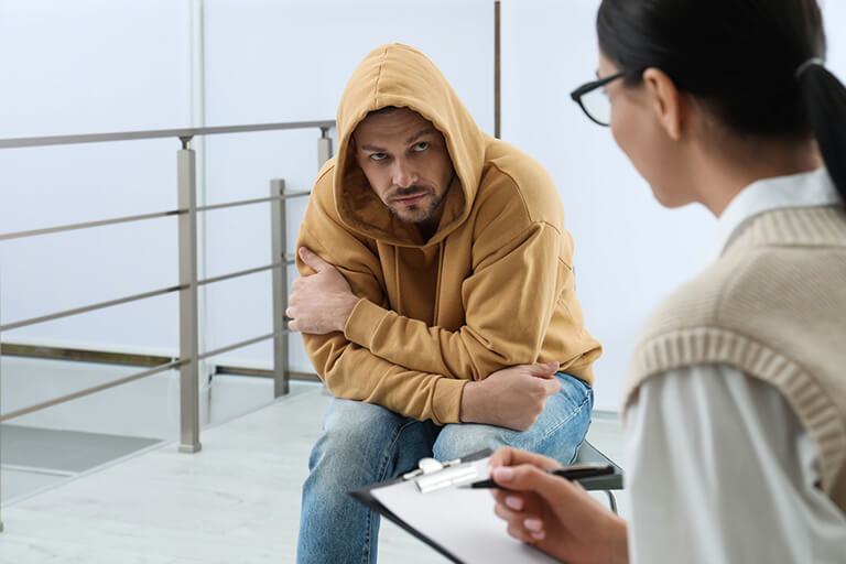 A person in a hoodie seeking help from a professional