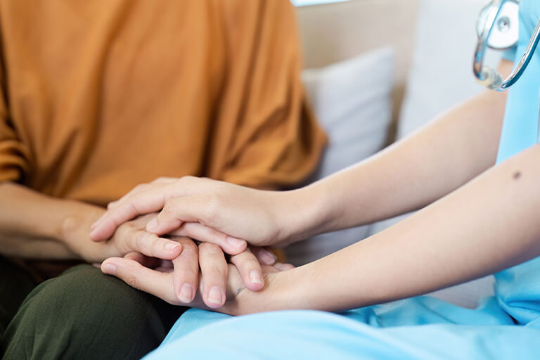 A healthcare professional holding a patient’s hands, giving them comfort