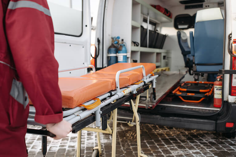 A paramedic pushing a stretcher into the back of an ambulance