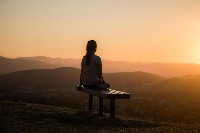 A woman sitting at a viewpoint, practicing mindfulness while resting from exercise