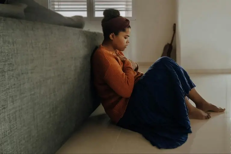 A woman sitting on the floor, experiencing excessive worry and rumination