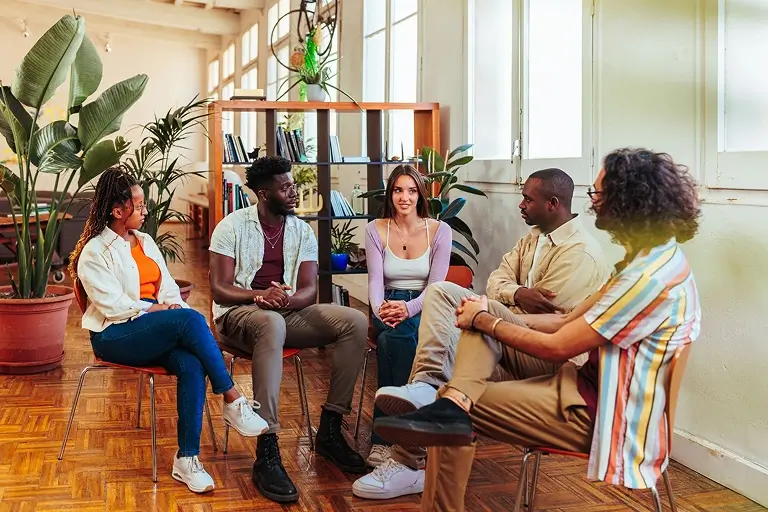 A group of people seated in a semi-circle during a group therapy session