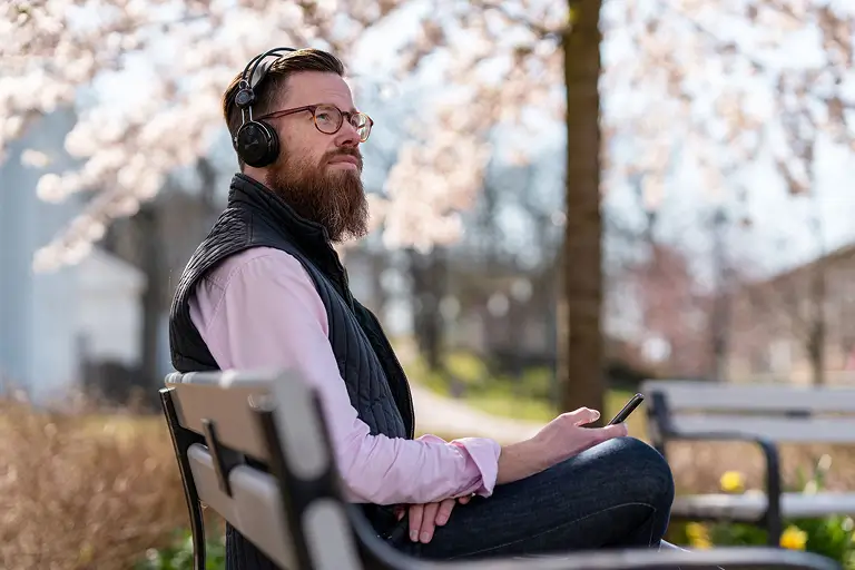 A man listening to a sobriety podcast while sitting at the park