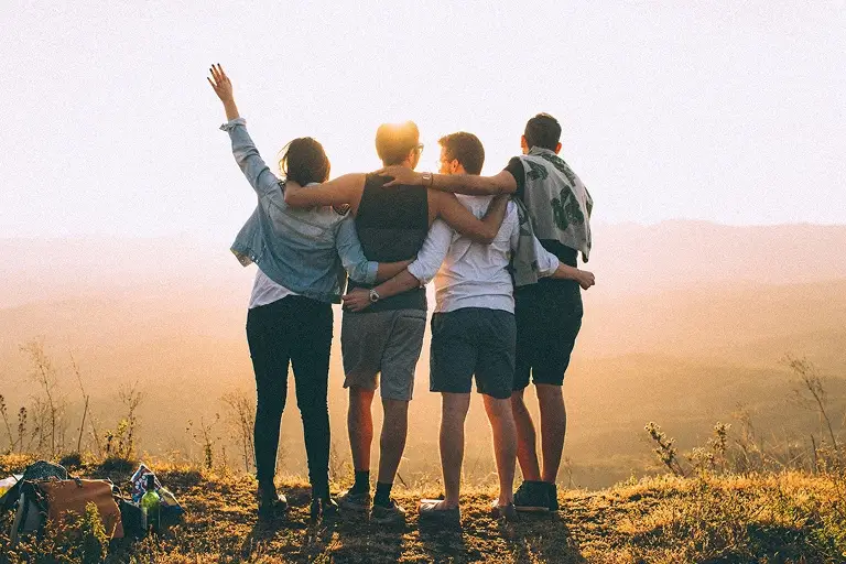 A group of friends on a hike watch the sunset.